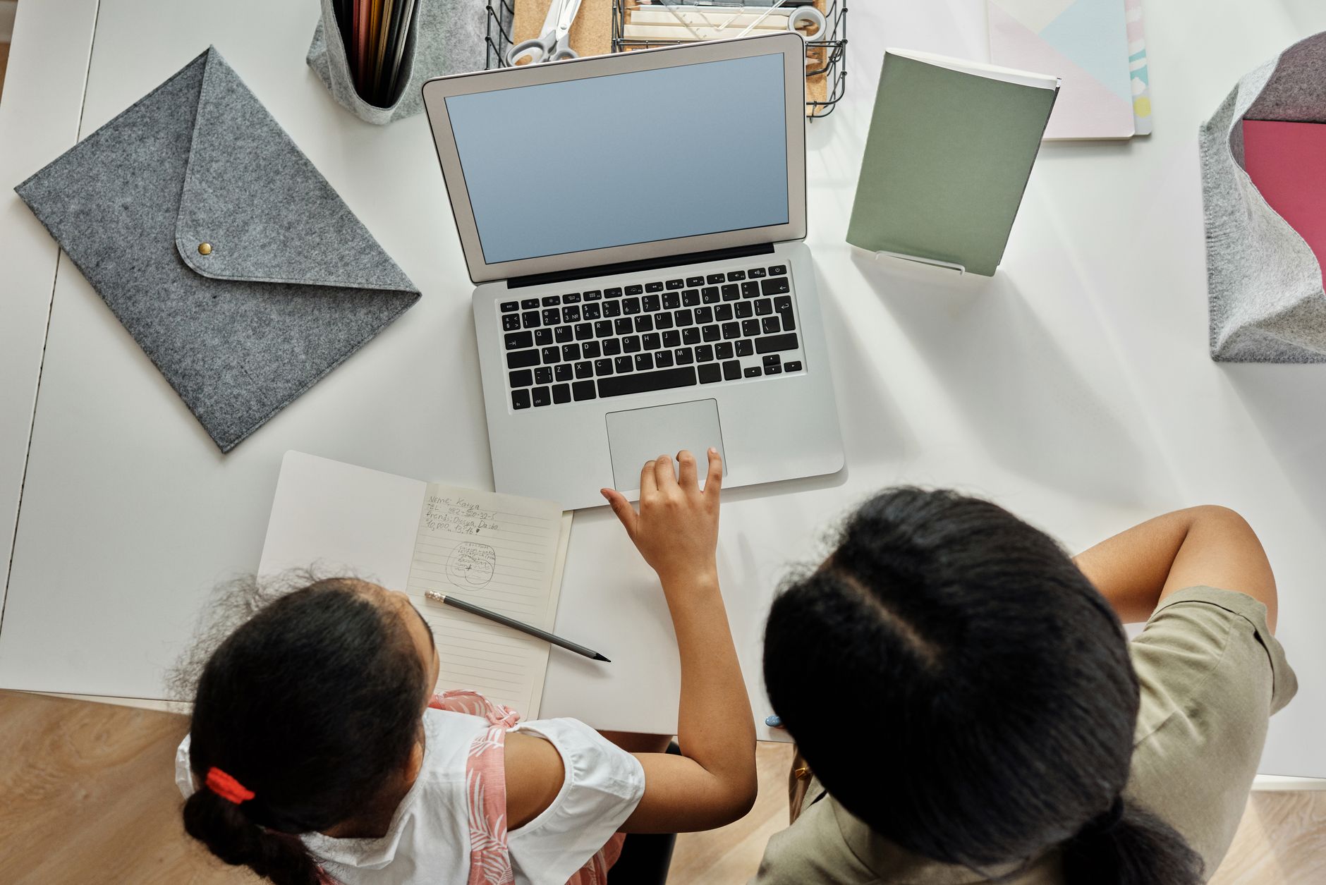 Parent helping a child with schoolwork on a laptop at home
