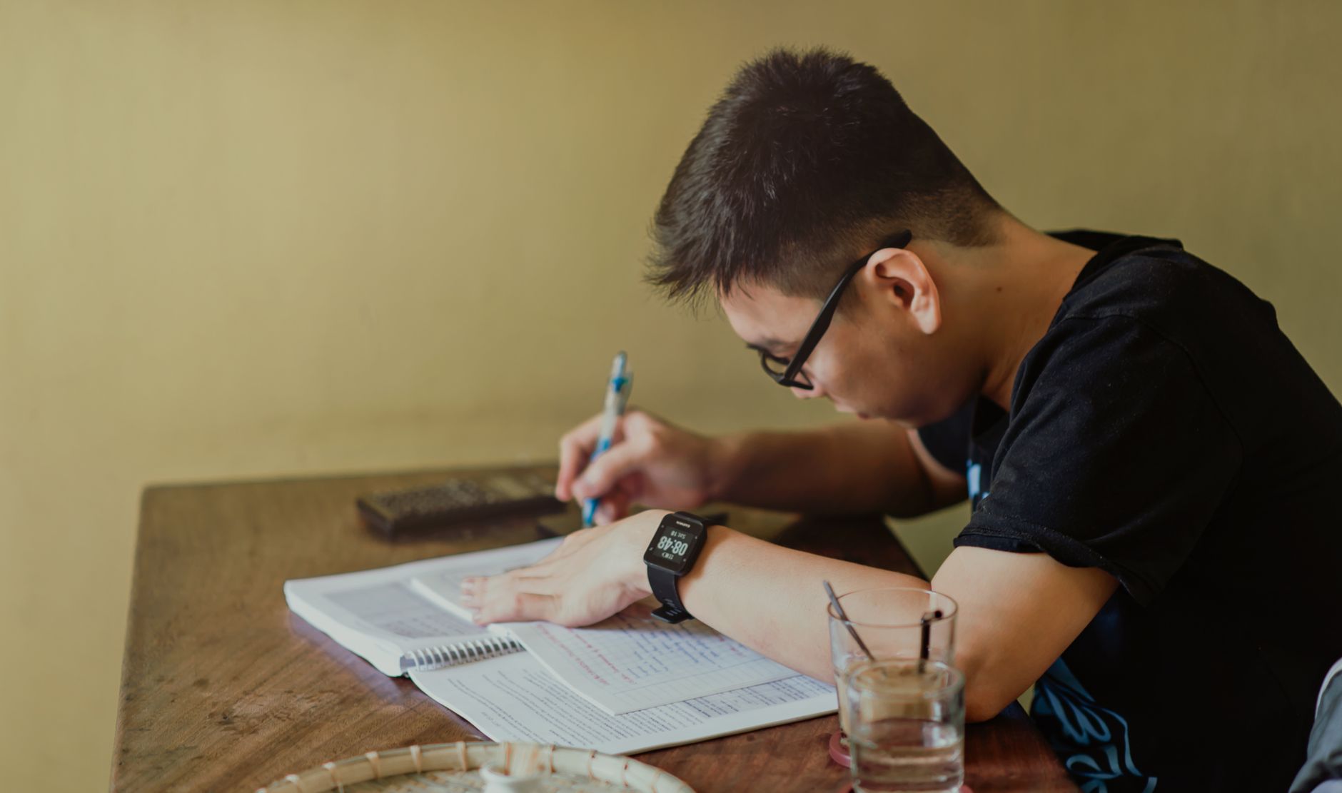 Student taking notes while studying at a desk
