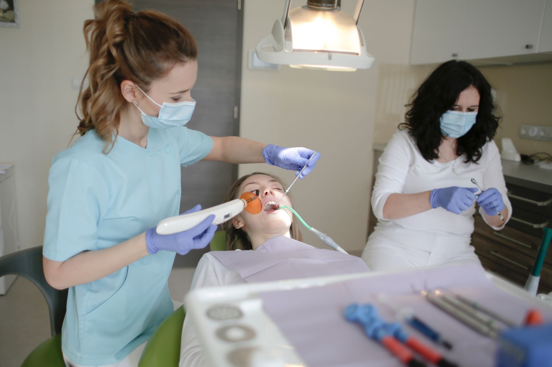 Dental assistant in scrubs holding a curing light